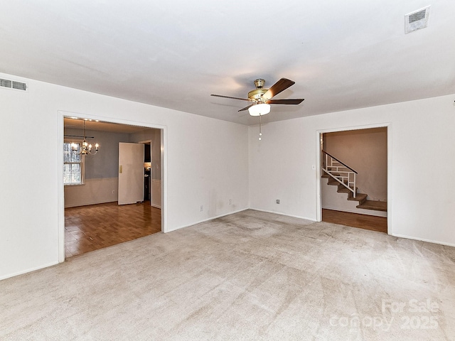 unfurnished living room with carpet flooring and ceiling fan with notable chandelier