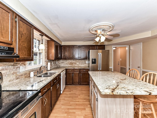 kitchen featuring a kitchen bar, high quality fridge, electric stove, sink, and a kitchen island