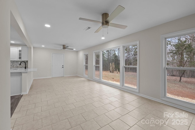 unfurnished living room featuring ceiling fan, sink, and light tile patterned flooring