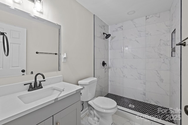 bathroom with tiled shower, vanity, and toilet