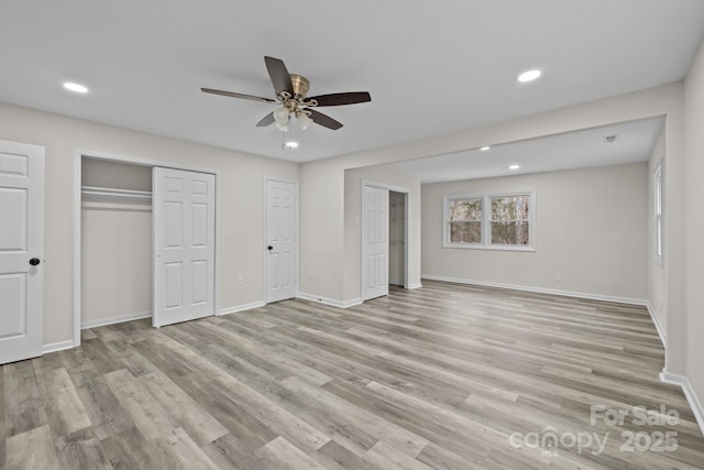 unfurnished bedroom with multiple closets, ceiling fan, and light hardwood / wood-style floors