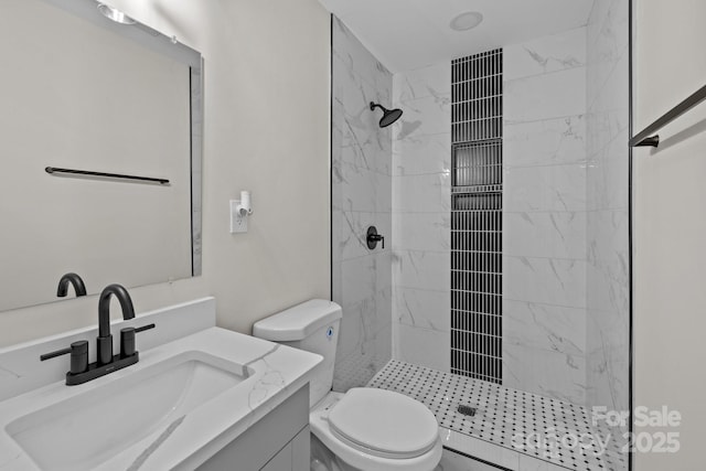 bathroom with a tile shower, vanity, and toilet