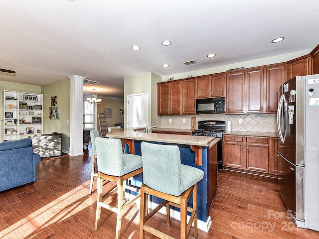 kitchen featuring a breakfast bar, dark wood-type flooring, an island with sink, and black appliances