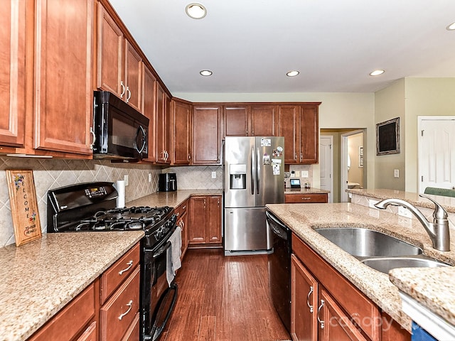 kitchen with sink, light stone counters, dark hardwood / wood-style flooring, backsplash, and black appliances