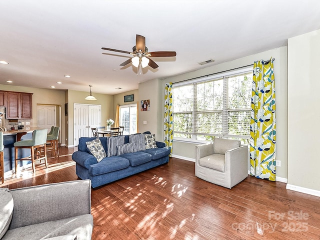 living room featuring ceiling fan and dark hardwood / wood-style flooring