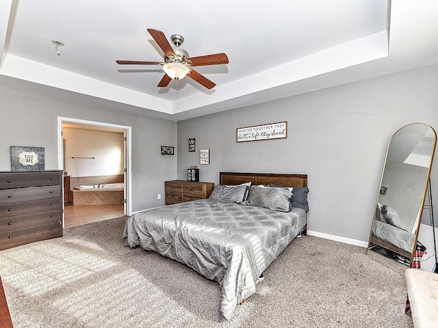 bedroom featuring carpet, ensuite bathroom, a raised ceiling, and ceiling fan