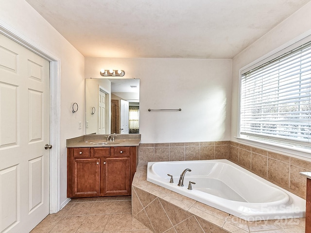 bathroom with tiled tub, tile patterned flooring, and vanity