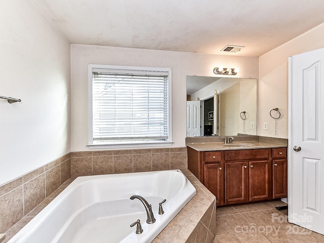 bathroom with tile patterned flooring, vanity, and tiled bath