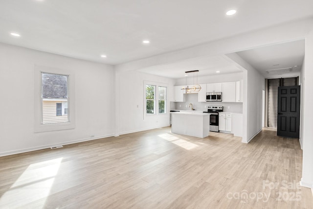 unfurnished living room featuring sink and light hardwood / wood-style floors