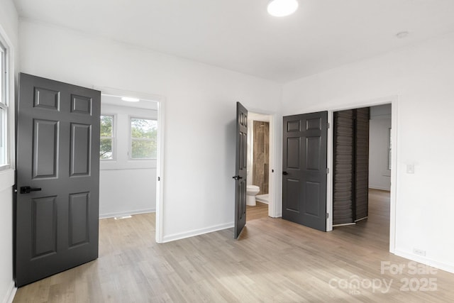 unfurnished bedroom with connected bathroom, a closet, and light wood-type flooring