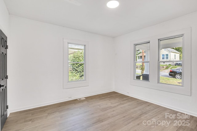 empty room featuring a wealth of natural light and hardwood / wood-style flooring