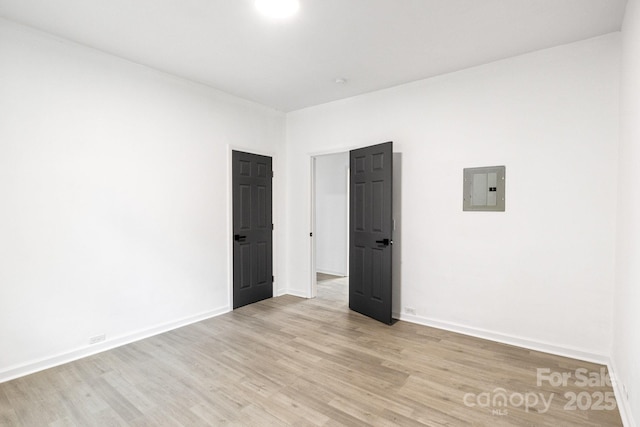 empty room with electric panel and light hardwood / wood-style floors