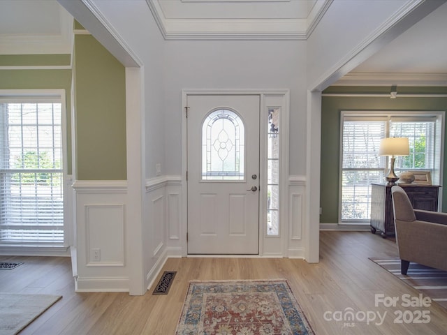 entryway with light hardwood / wood-style floors and ornamental molding