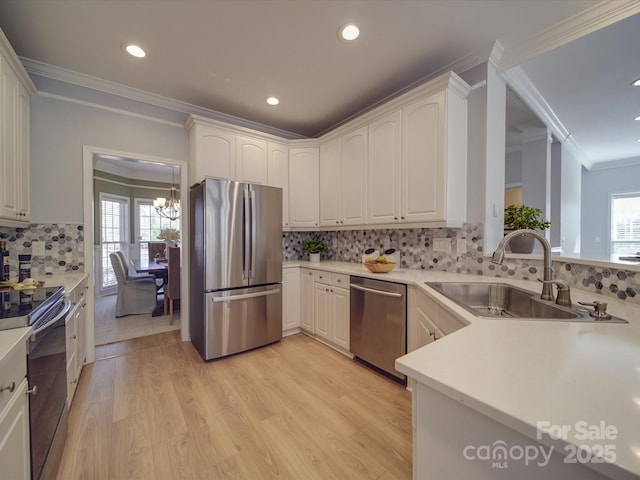 kitchen featuring sink, stainless steel appliances, an inviting chandelier, crown molding, and light wood-type flooring