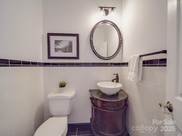 bathroom with tile patterned flooring, vanity, toilet, and tile walls