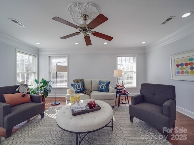 living room featuring ceiling fan, ornamental molding, and a wealth of natural light