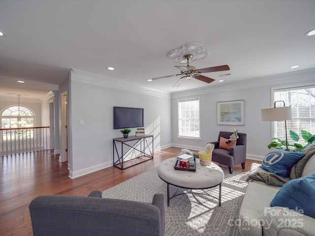 living room with hardwood / wood-style floors, ceiling fan with notable chandelier, and ornamental molding