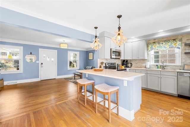 kitchen featuring sink, a kitchen bar, hanging light fixtures, a center island, and stainless steel appliances