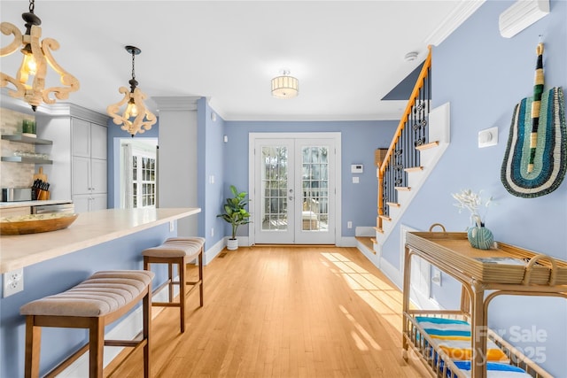 interior space with crown molding, light hardwood / wood-style floors, and french doors