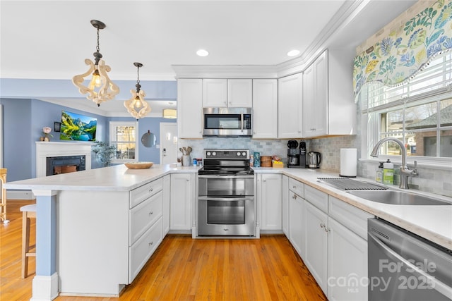 kitchen featuring appliances with stainless steel finishes, decorative light fixtures, white cabinets, and kitchen peninsula