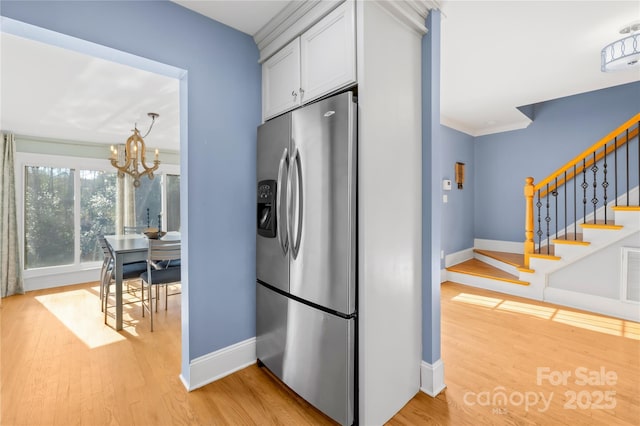 kitchen with white cabinets, a notable chandelier, stainless steel fridge, and light hardwood / wood-style floors