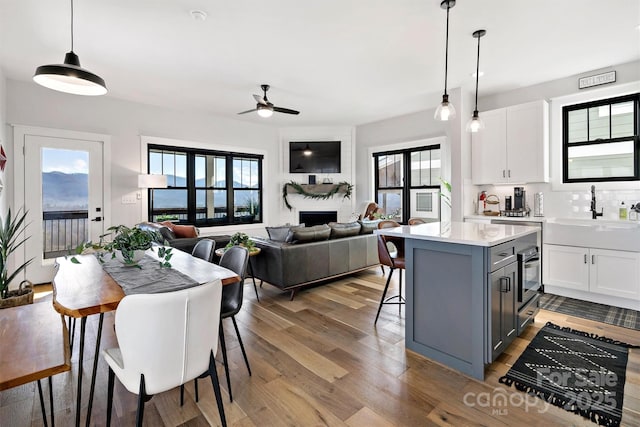 kitchen with white cabinetry, sink, ceiling fan, and hanging light fixtures