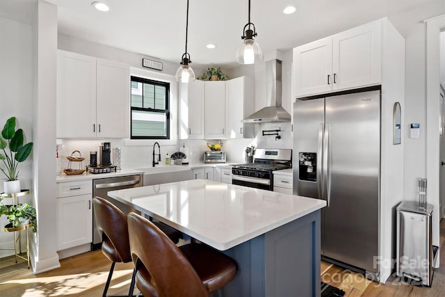 kitchen with a kitchen island, stainless steel appliances, white cabinetry, and wall chimney exhaust hood