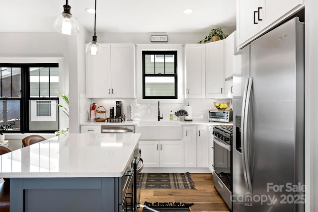 kitchen featuring white cabinets, pendant lighting, stainless steel appliances, and sink