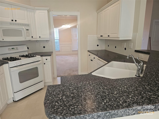 kitchen featuring white appliances, a chandelier, sink, white cabinetry, and tasteful backsplash