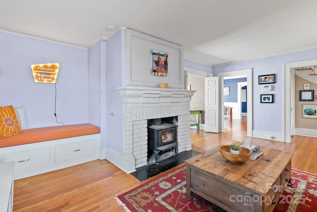 living room with hardwood / wood-style flooring, a wood stove, and crown molding