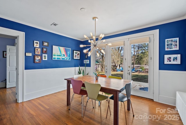 dining area featuring wood-type flooring, crown molding, radiator, and french doors