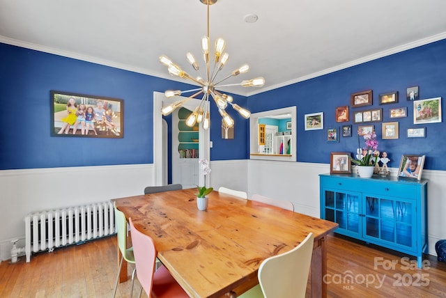 dining space featuring crown molding, radiator heating unit, a chandelier, and wood-type flooring