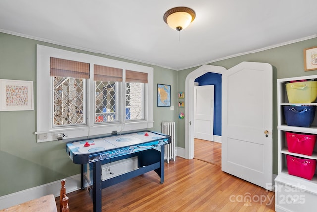 playroom with crown molding, radiator heating unit, and light hardwood / wood-style flooring