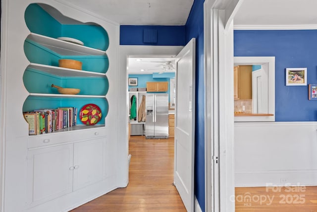 hallway featuring crown molding and light hardwood / wood-style flooring