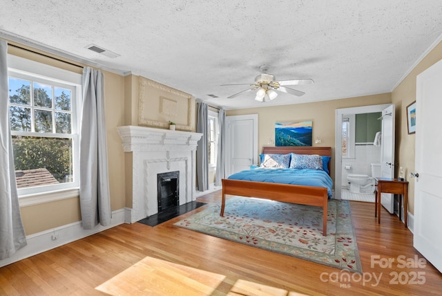 bedroom with ceiling fan, wood-type flooring, a textured ceiling, and multiple windows