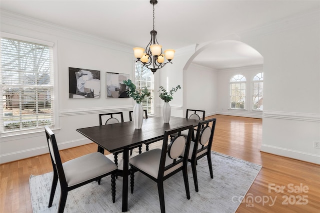 dining area with ornamental molding, a chandelier, and light hardwood / wood-style flooring