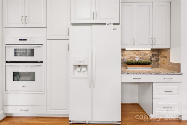 kitchen with light stone counters, white cabinets, and white appliances