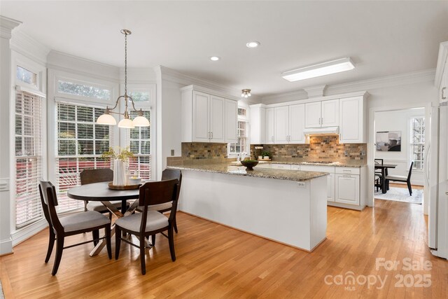 kitchen with white cabinetry, pendant lighting, light hardwood / wood-style floors, and kitchen peninsula