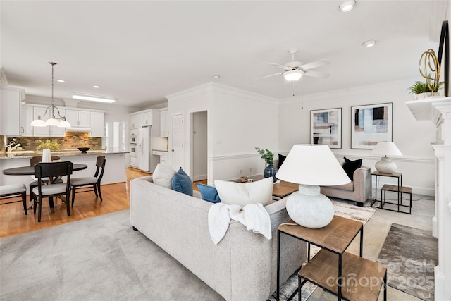 living room featuring ceiling fan, ornamental molding, sink, and light hardwood / wood-style floors