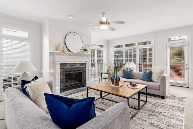 carpeted living room featuring crown molding, a premium fireplace, and ceiling fan