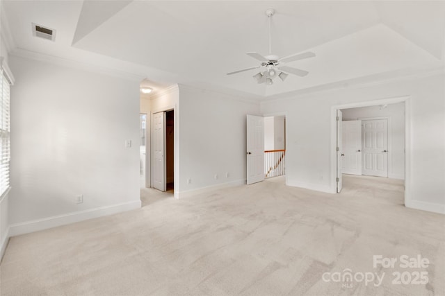 carpeted spare room with crown molding, ceiling fan, and a tray ceiling