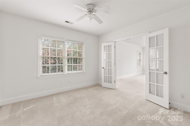 empty room featuring light carpet, ceiling fan, and french doors