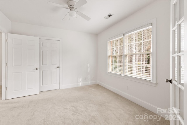 unfurnished bedroom featuring ceiling fan, a closet, and light carpet