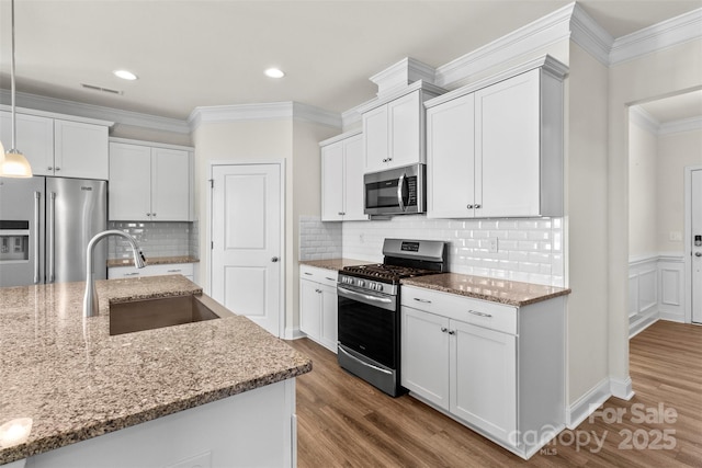 kitchen featuring light stone countertops, sink, hanging light fixtures, white cabinets, and appliances with stainless steel finishes