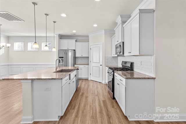 kitchen featuring white cabinetry, stainless steel appliances, an island with sink, pendant lighting, and decorative backsplash