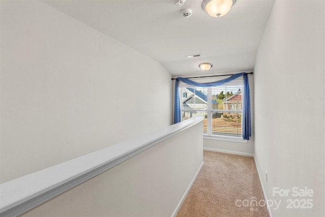 hall featuring light colored carpet and lofted ceiling