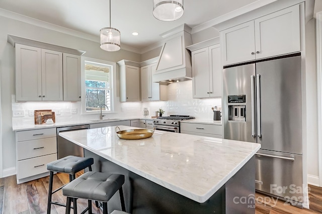 kitchen with pendant lighting, sink, a center island, high quality appliances, and custom exhaust hood