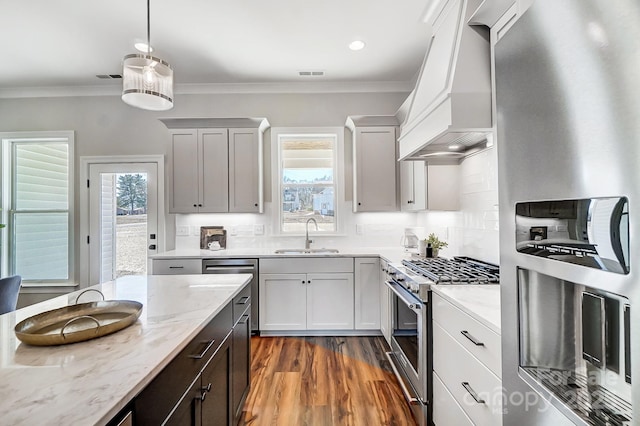 kitchen featuring sink, crown molding, appliances with stainless steel finishes, light stone countertops, and custom exhaust hood