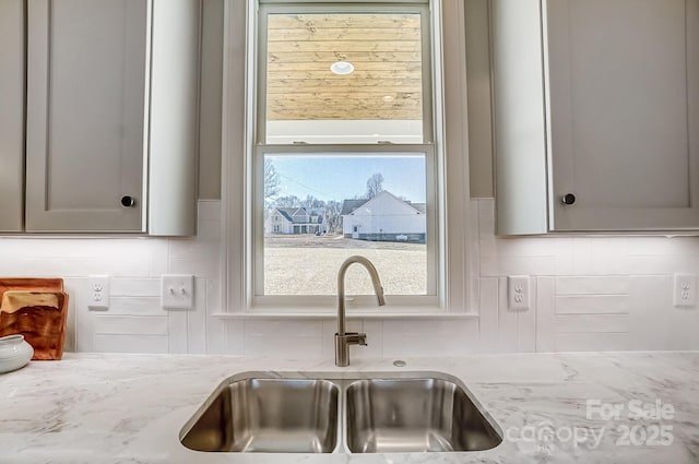 kitchen with light stone countertops, sink, and backsplash