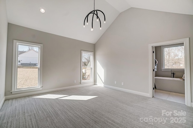 unfurnished living room with plenty of natural light, light carpet, a notable chandelier, and high vaulted ceiling